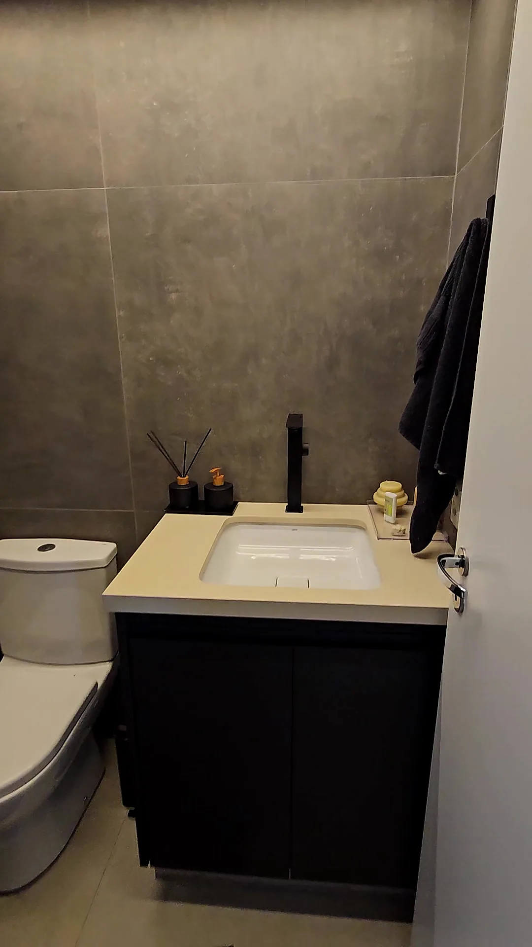 Lavabo com gabinete preto, bancada clara e metais pretos